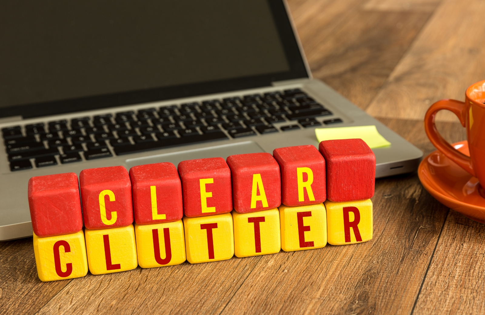 clear clutter sign in wooden blocks with laptop and coffee background