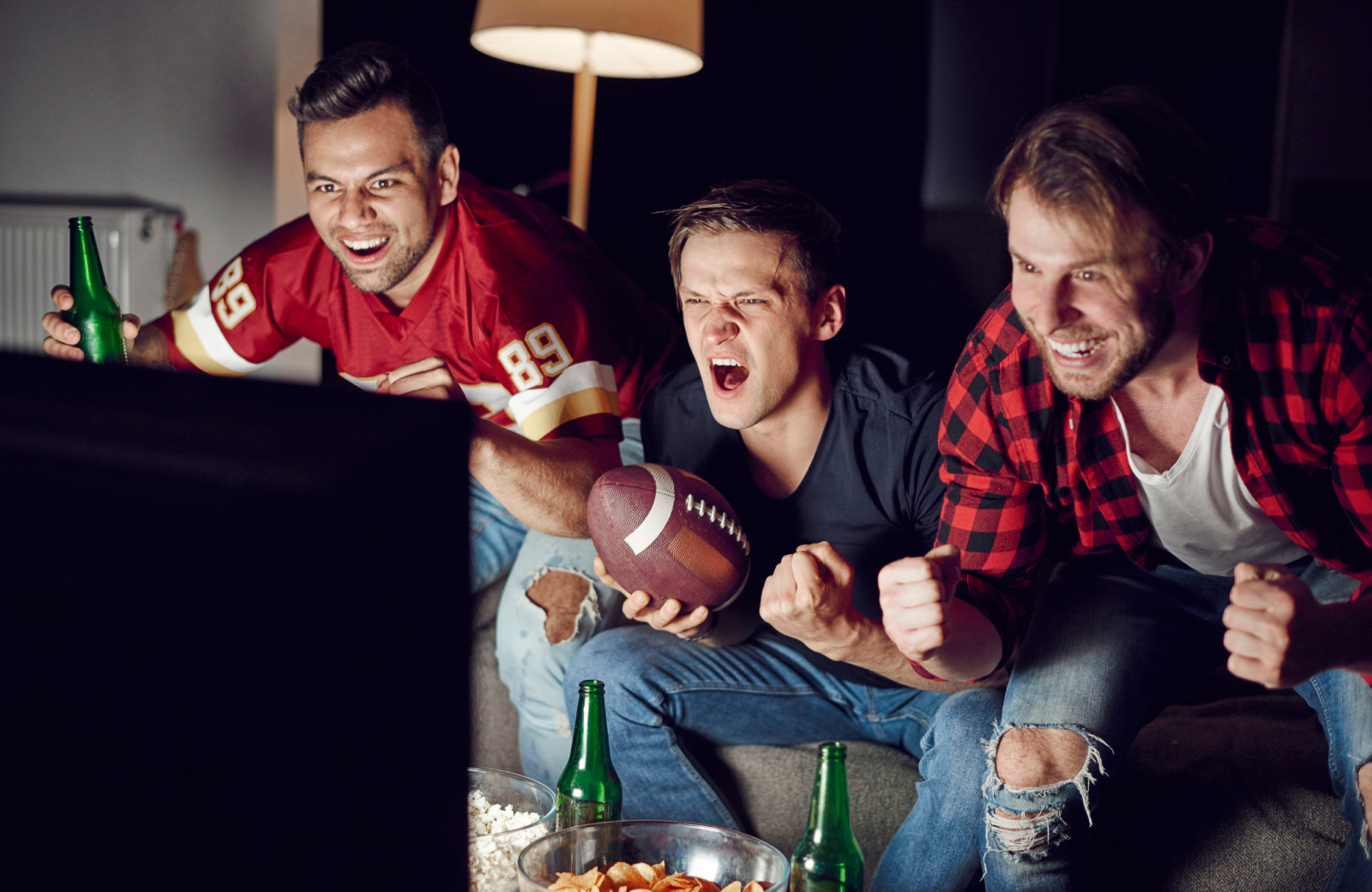 men excitedly watching football on tv