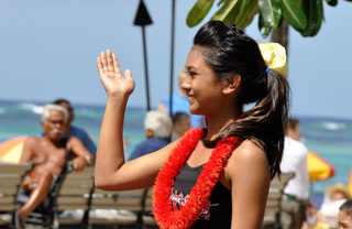 A woman wearing a lei waving