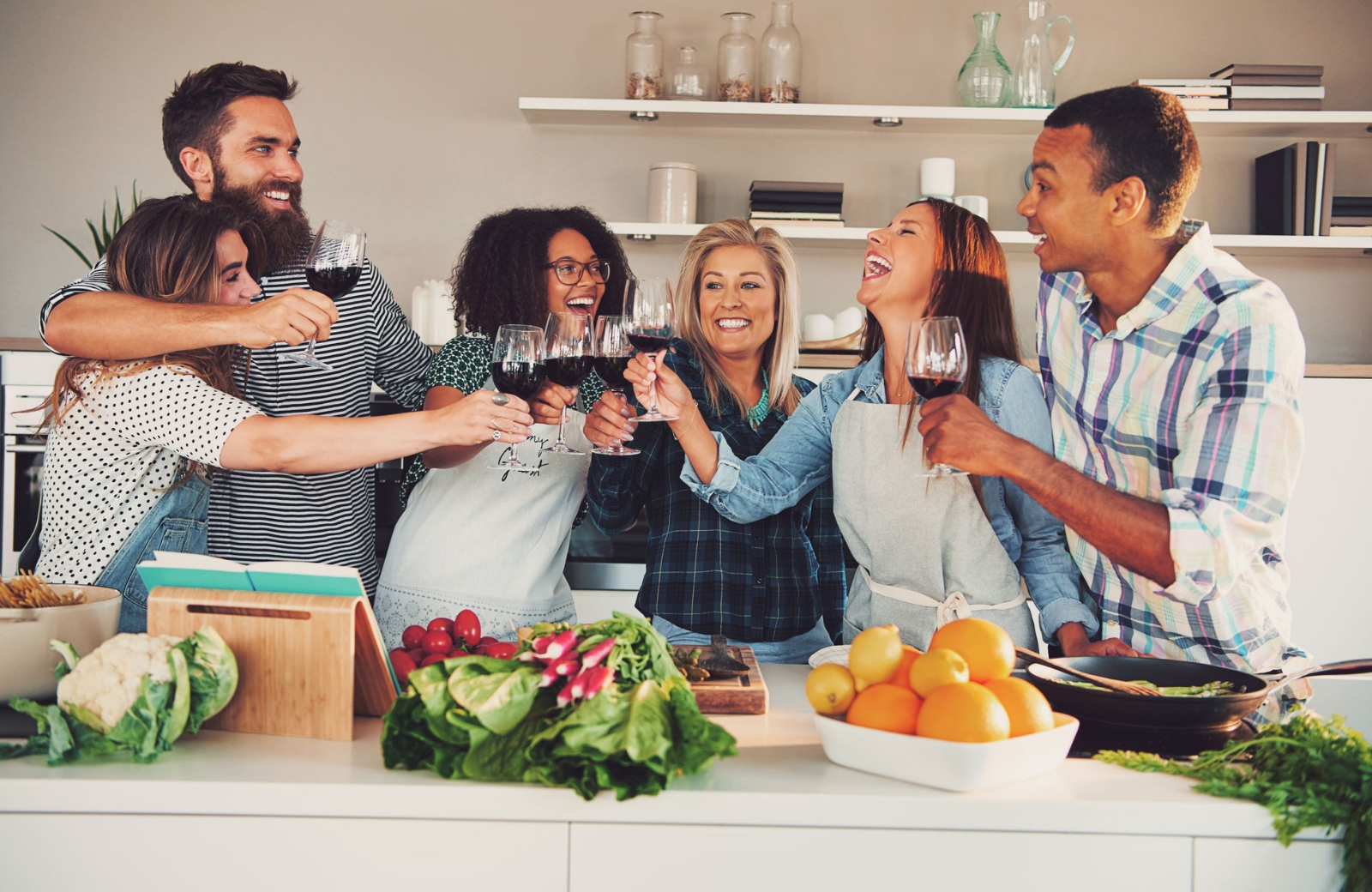 group of friends toasting wine in kitchen