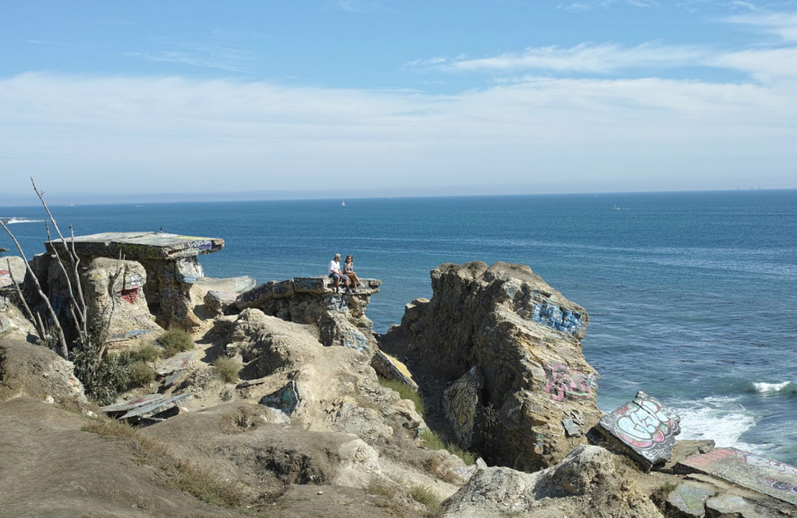 couple sitting on huge a rock boulder beside the sea
