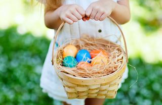 A little kid holding an easter basket with eggs in it