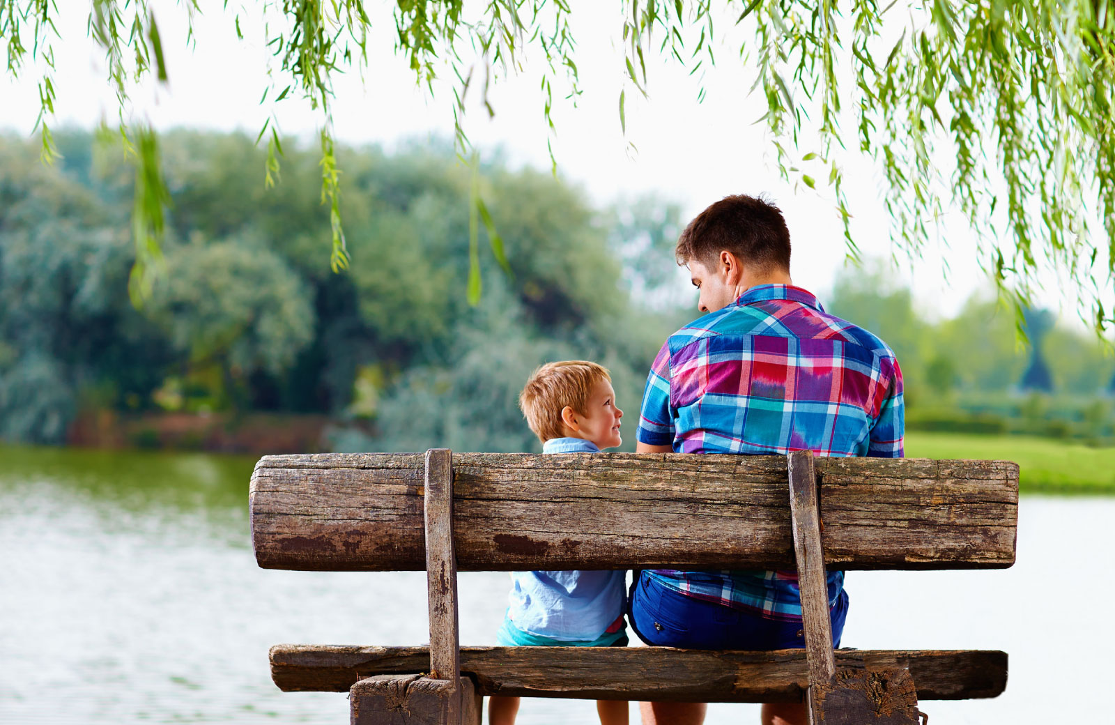 father and son hanging out at the park by the lake