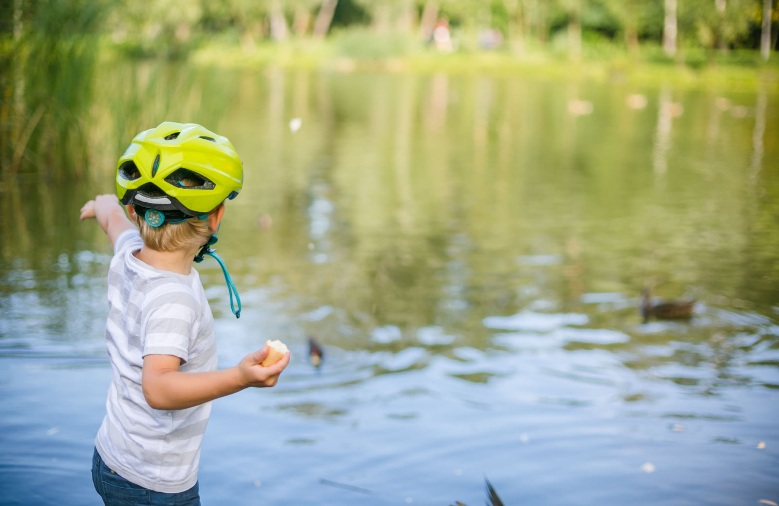 child with helmet playing by the lake