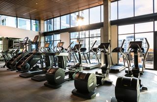 Indoor gym with treadmill machines facing big window at Hyde Square apts