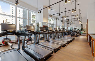 Fitness room with rowing machines, weight benches, medicine balls, a punching bag, and yoga mats.