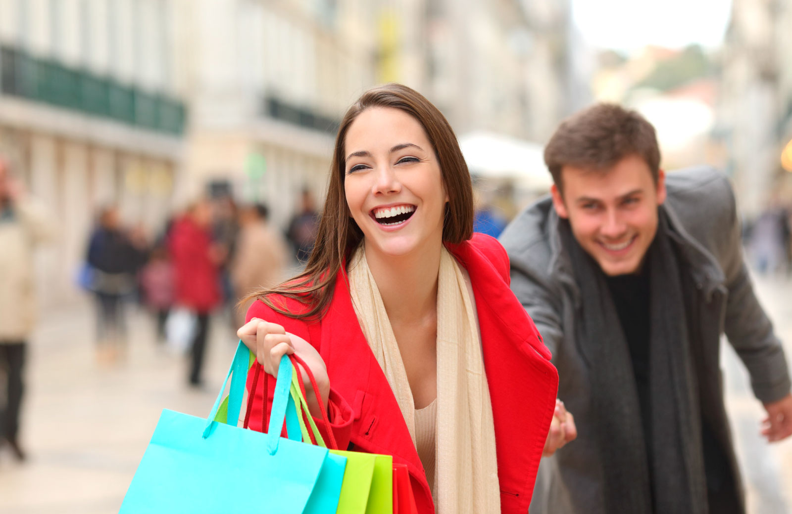 woman smiling with shopping bags and holding man's hand
