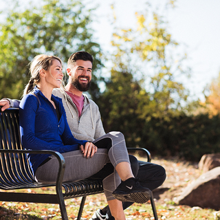 A couple sitting on a park bench on a bright day