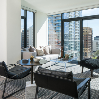 Atelier Apartment living room with white couch and black chairs facing windows with city views