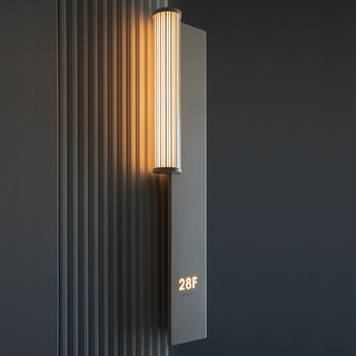 Close up of a sleek, vertical wall sconce on gray walls in the building's hallway.